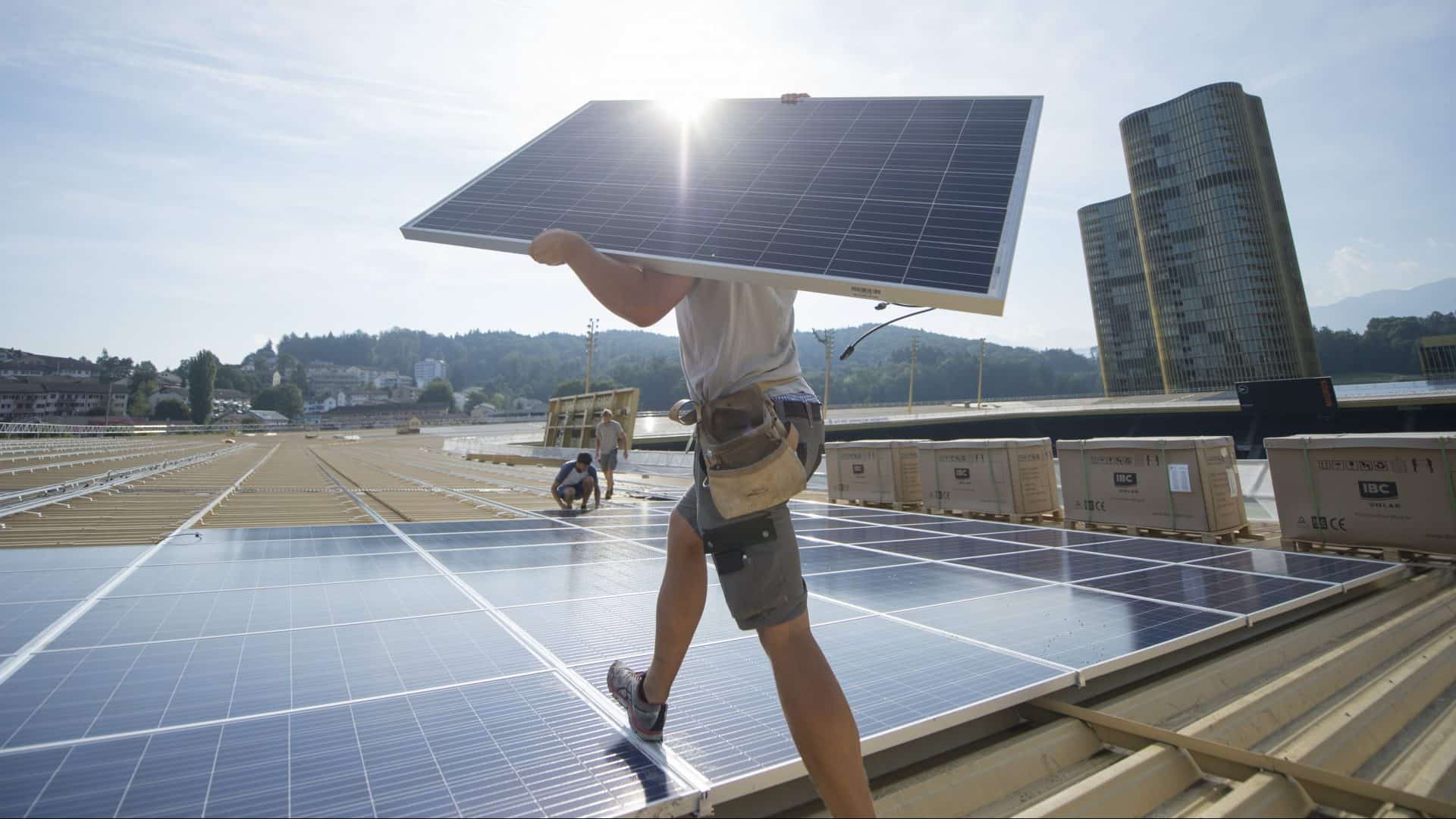 Bauarbeiter trägt Solarpanel auf Dach